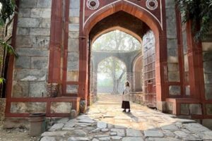 Historická brána Červené pevnosti v Dillí s návštěvníkem stojícím uprostřed kamenné cesty.