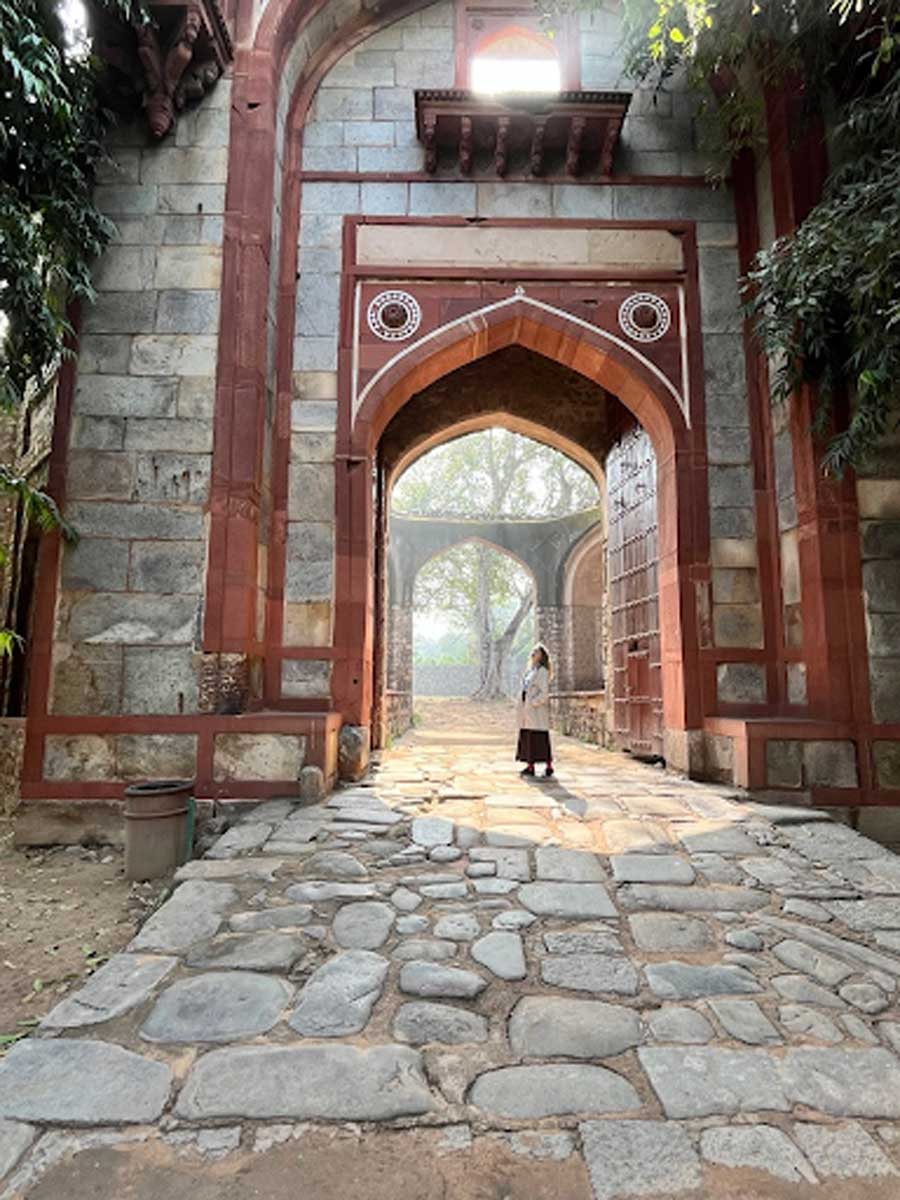 Historická brána Červené pevnosti v Dillí s návštěvníkem stojícím uprostřed kamenné cesty.