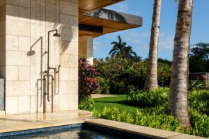 Venkovní sprcha a bazén obklopený tropickou zahradou a palmami