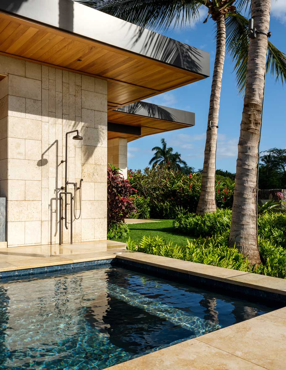 Venkovní sprcha a bazén obklopený tropickou zahradou a palmami