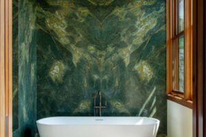 Koupelna s volně stojící vanou a výraznou kamennou stěnou v zelených tónech