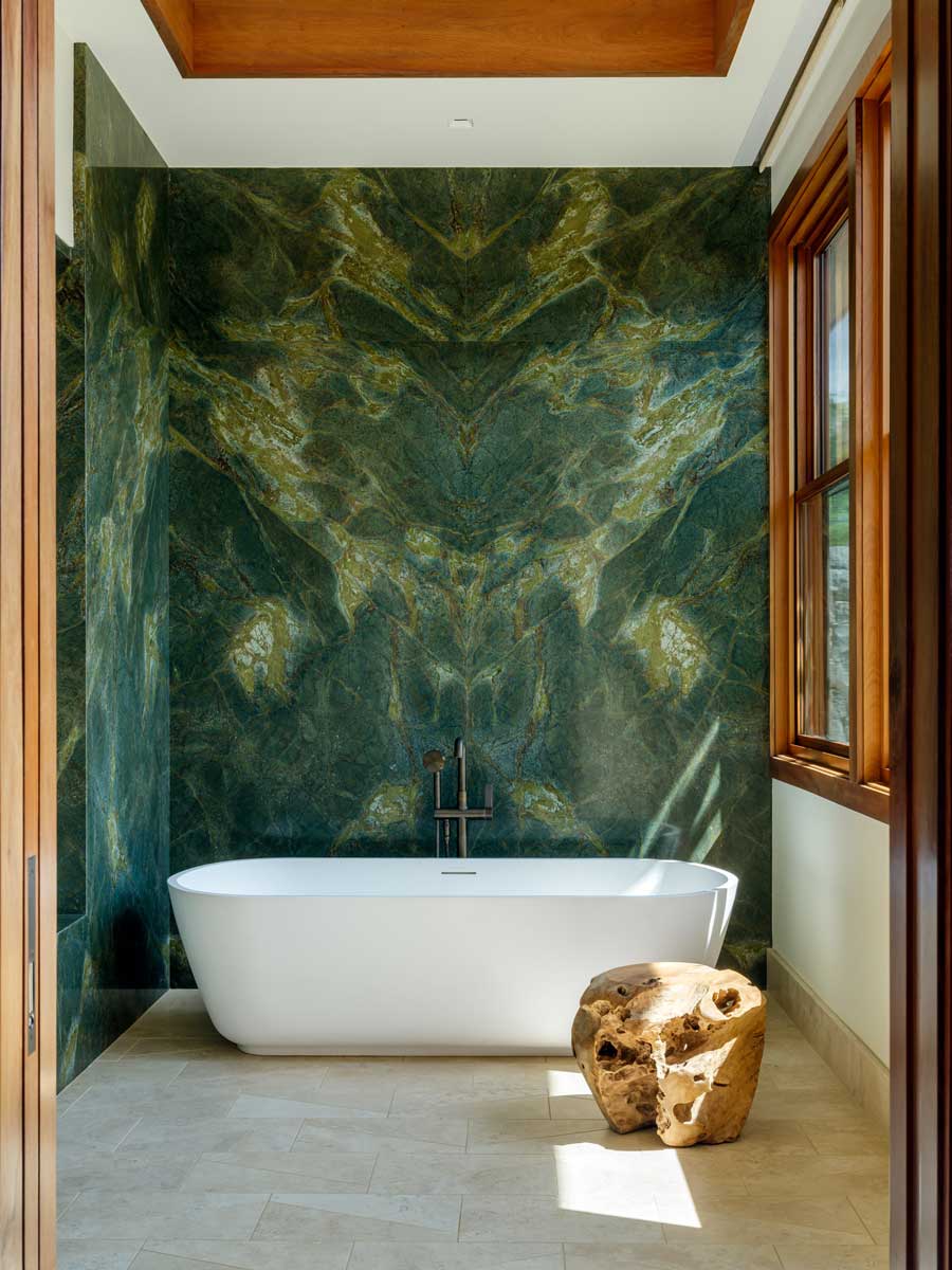 Koupelna s volně stojící vanou a výraznou kamennou stěnou v zelených tónech