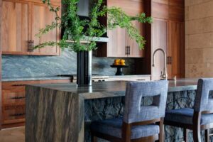 Kuchyň s masivním kamenným ostrůvkem, dřevěnými skříňkami a přírodními materiály