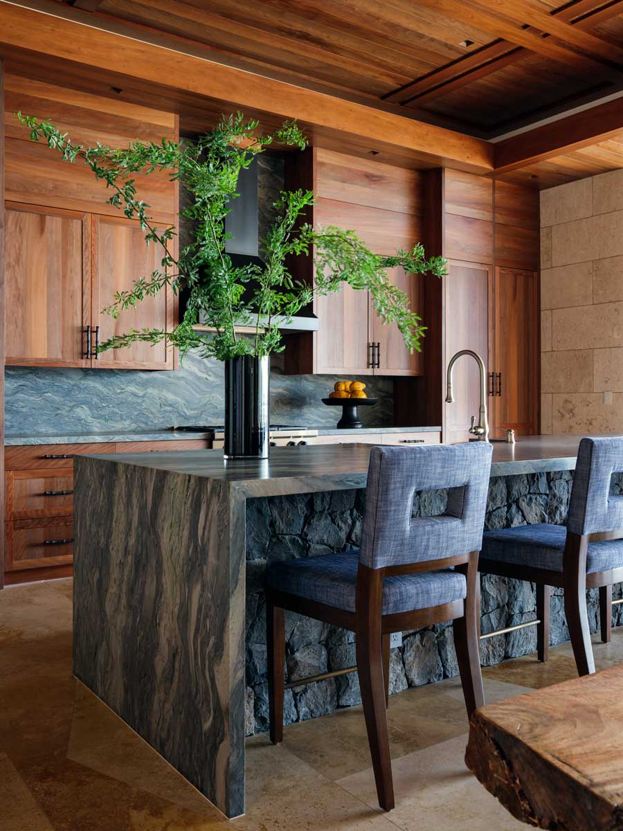 Kuchyň s masivním kamenným ostrůvkem, dřevěnými skříňkami a přírodními materiály