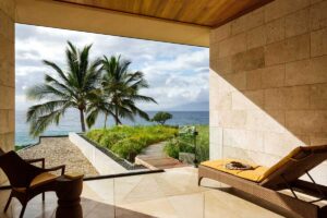 Krytá terasa s lehátkem a výhledem na oceán a palmy v tropické zahradě