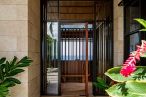 Vstup do domu obklopený tropickou zelení a přírodními materiály