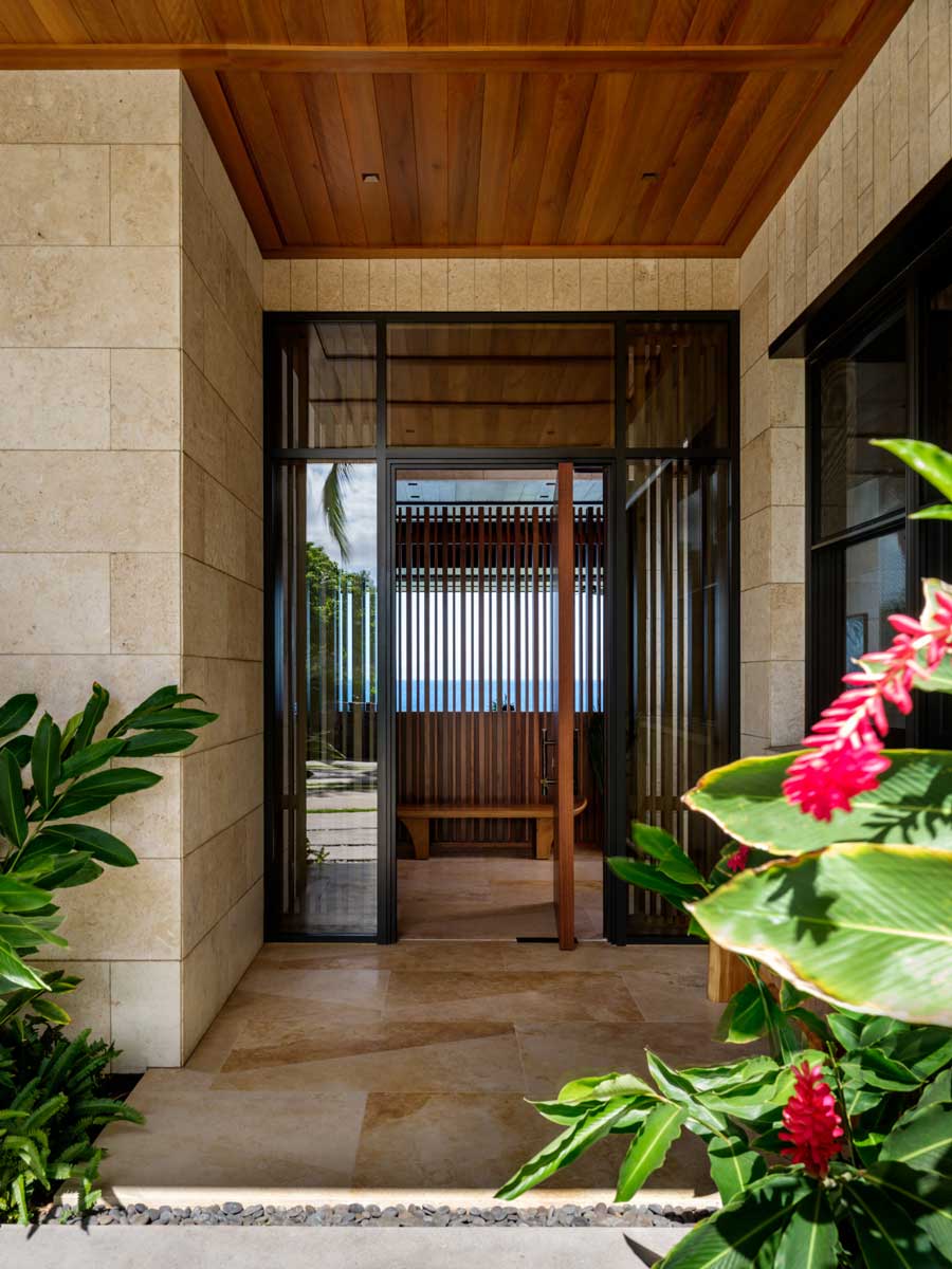 Vstup do domu obklopený tropickou zelení a přírodními materiály