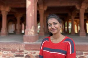 Mladá Indka usmívající se před historickou architekturou v Dillí.