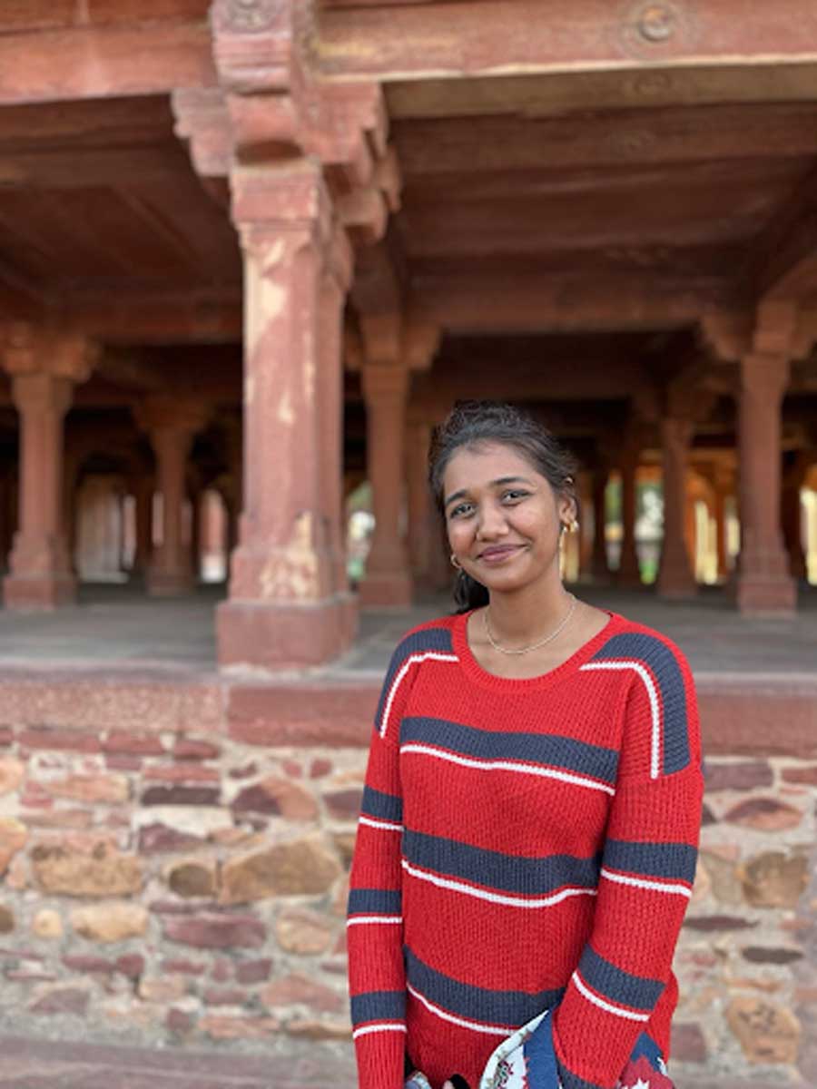 Mladá Indka usmívající se před historickou architekturou v Dillí.