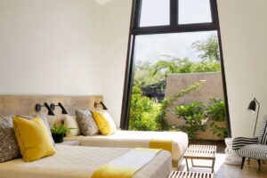 Ložnice s vysokým stropem, velkým oknem a výhledem do zeleně