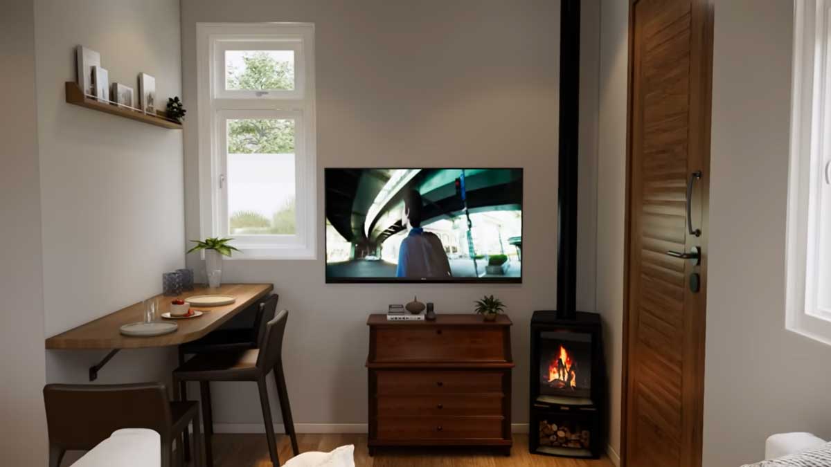 Obytný prostor tiny house s jídelním stolem, televizí a krbovými kamny.