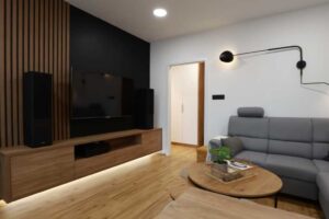 Televizní stěna s dřevěným obkladem a černým panelem vytváří výrazný designový prvek obývacího pokoje.