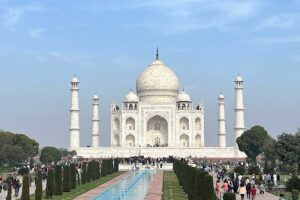 Tádž Mahal v Indii při denním světle s turisty procházejícími se kolem slavného památníku.