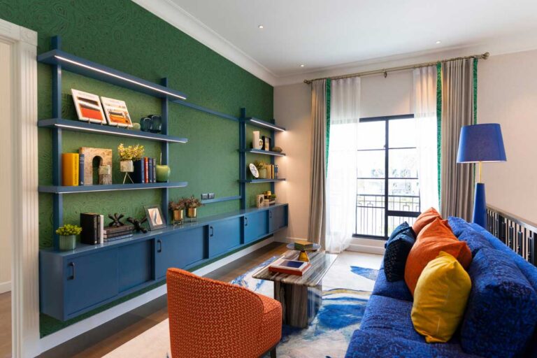 Barevný obývací pokoj s modrou sedačkou oranžovým křeslem a výraznou zelenou stěnou