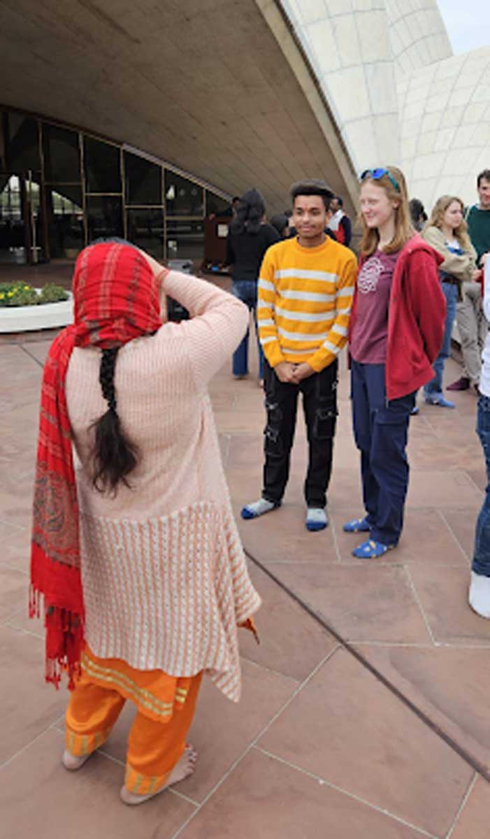 Indická žena fotografuje evropské turisty před moderní budovou v Indii.