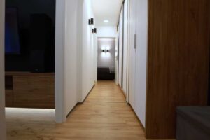 Dlouhá světlá chodba s vestavěnými skříněmi a dřevěnou podlahou působí vzdušně a přehledně.