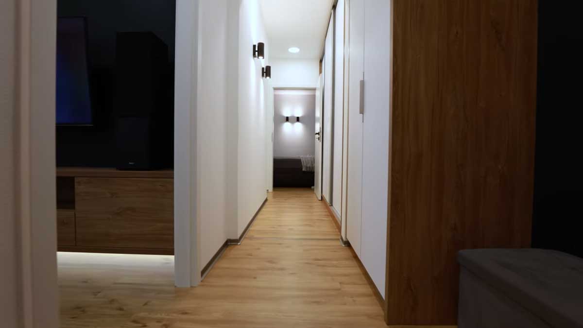 Dlouhá světlá chodba s vestavěnými skříněmi a dřevěnou podlahou působí vzdušně a přehledně.