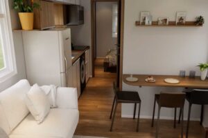 Multifunkční obytný prostor tiny house s kuchyní, jídelním koutem a pohovkou.