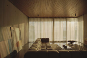 Tlumeně osvětlený obývací pokoj s měkkou pohovkou a vysokými závěsy působí klidně a útulně.