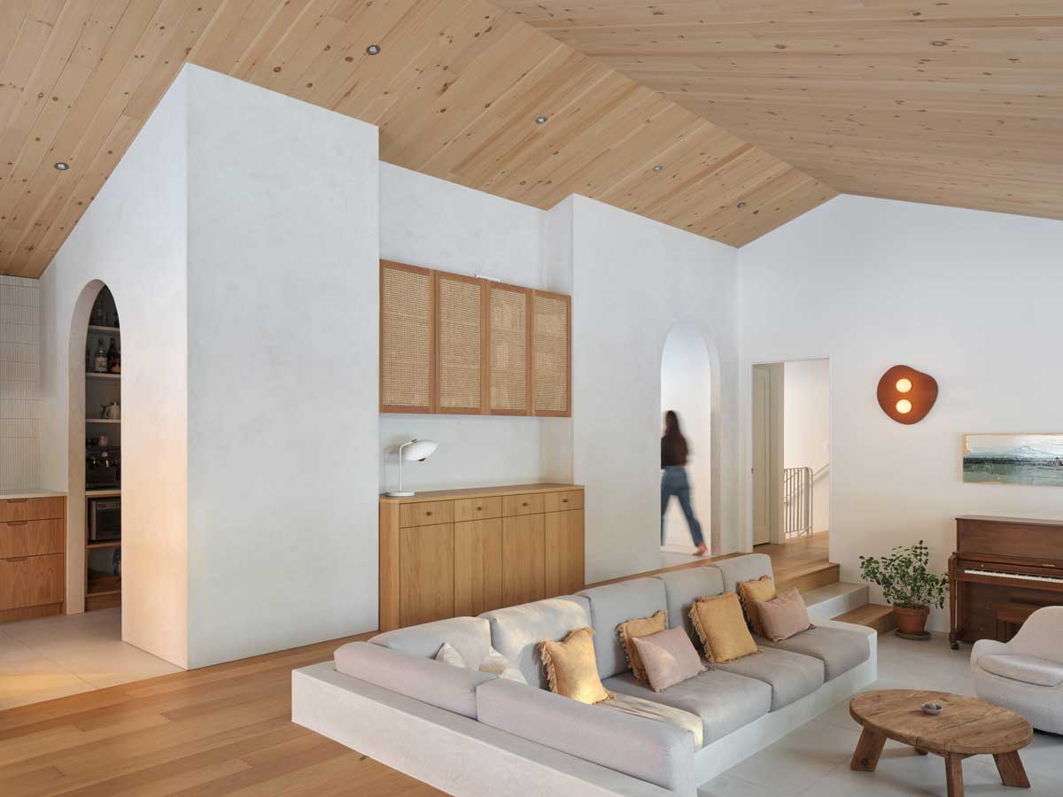 Obývací prostor s dřevěným nábytkem, obloukovými průchody a otevřenou dispozicí působí vzdušně a přirozeně