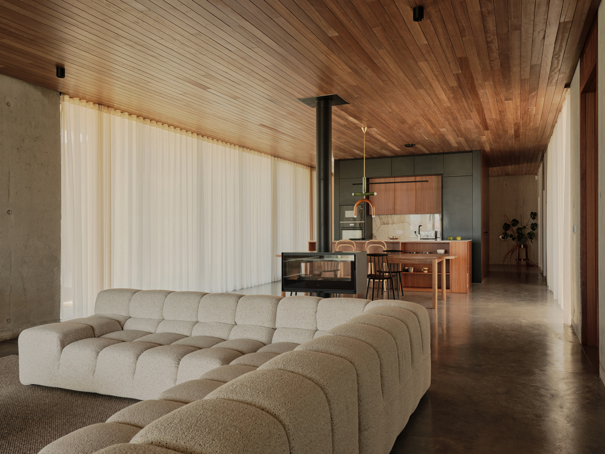 Prostorná denní zóna s designovým krbem, kuchyní a velkou pohovkou působí vzdušně a elegantně.