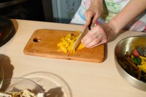 Krájení zeleniny na prkénku jako příklad efektivní přípravy surovin před samotným vařením.