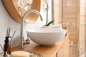 Upravená koupelna s čistým umyvadlem a jemnými doplňky působí svěže a pečlivě.