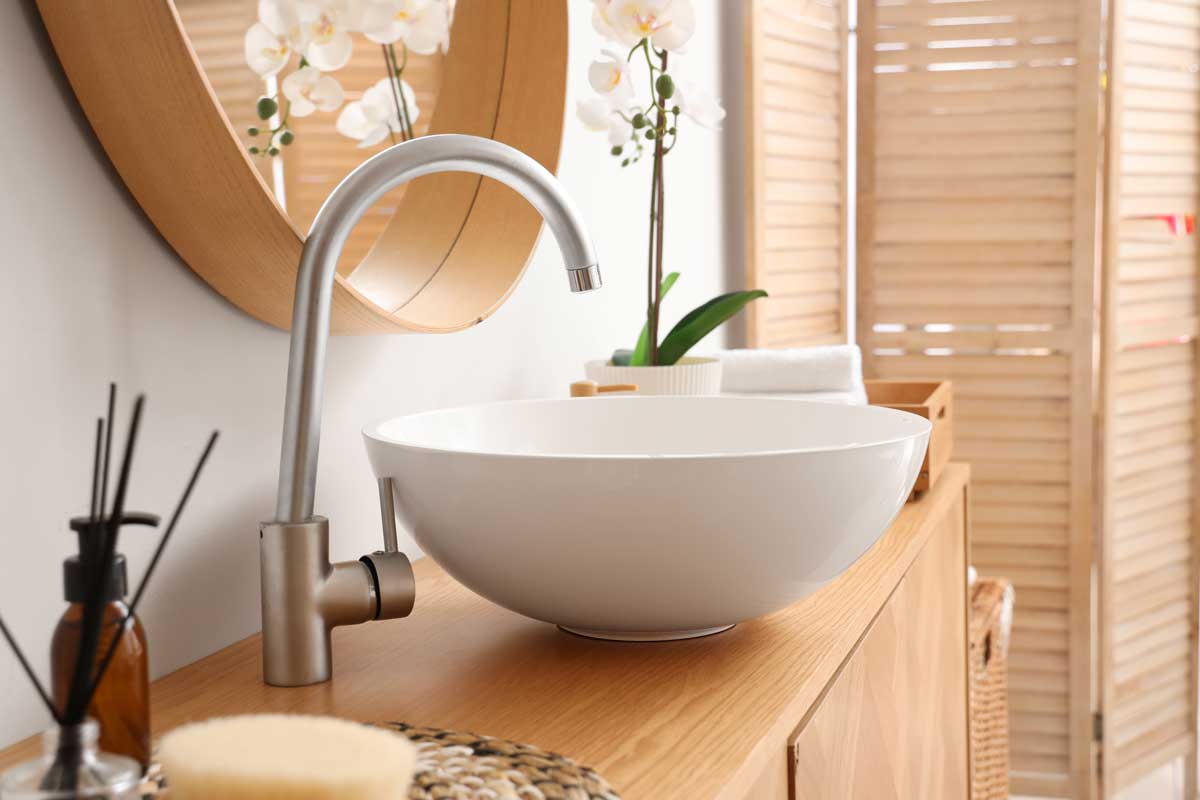 Upravená koupelna s čistým umyvadlem a jemnými doplňky působí svěže a pečlivě.