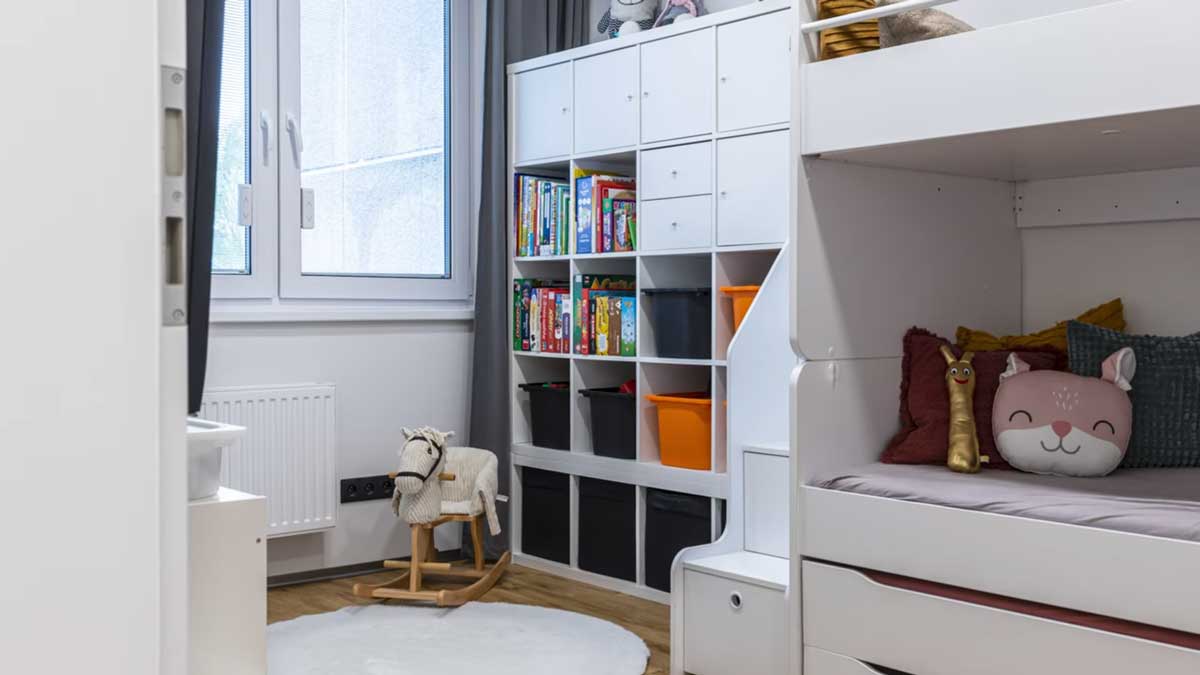 Dětský pokoj s patrovou postelí úložnými prostory a světlým nábytkem působí prakticky a zároveň hravě.