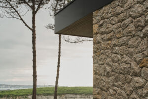 Detail kamenné fasády domu ukazuje spojení tradičního materiálu a současných architektonických linií.