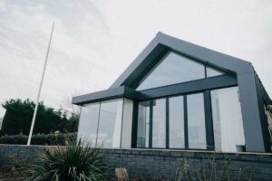 Moderní rodinný dům s rozsáhlým prosklením v hustší zástavbě kde je patrná menší míra soukromí.