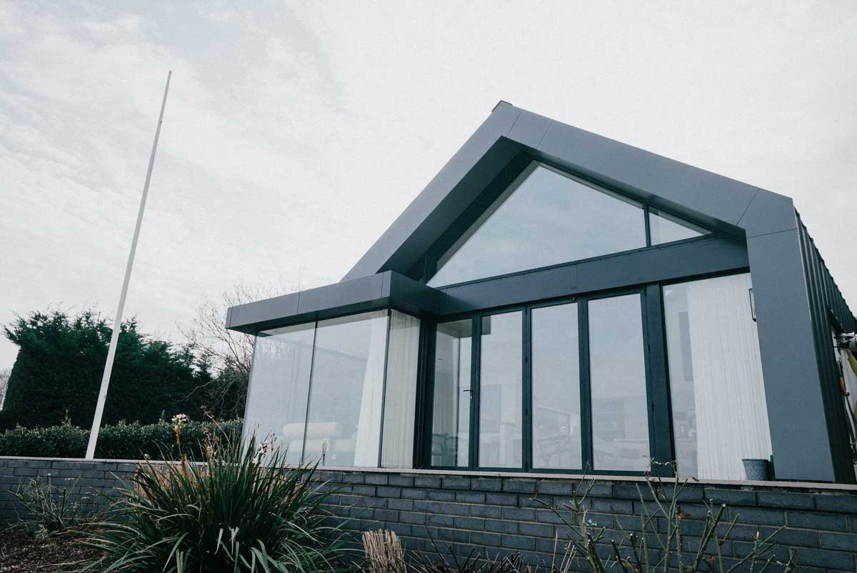 Moderní rodinný dům s rozsáhlým prosklením v hustší zástavbě kde je patrná menší míra soukromí.