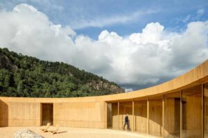 Vnější část domu s obloukovou stěnou a otevřeným nádvořím pod dramatickou oblohou.