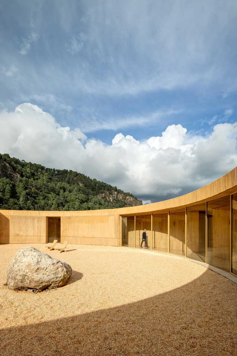 Vnější část domu s obloukovou stěnou a otevřeným nádvořím pod dramatickou oblohou.