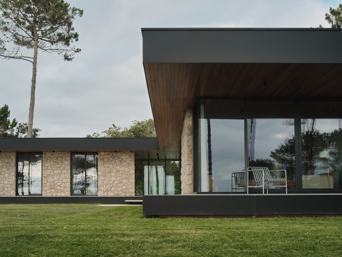 Prosklený roh domu s krytou terasou nabízí klidné posezení a výhled do zeleně.