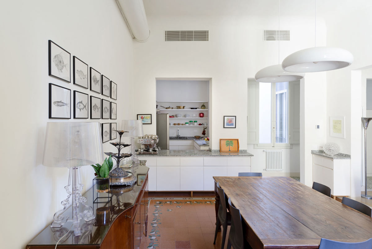 Jídelna s velkým dřevěným stolem, designovými svítidly a navazující kuchyní nabízí prostor pro společná setkání.