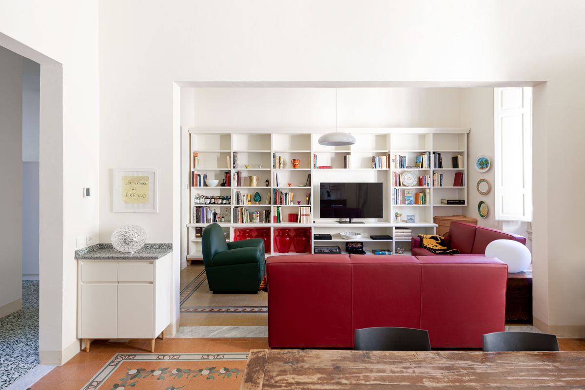 Pohled z jídelny do obývacího pokoje ukazuje otevřenou dispozici, vestavěnou knihovnu a výrazné barevné akcenty.