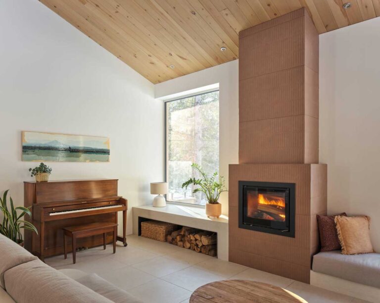 Obývací kout s klavírem, krbem a velkým oknem vytváří útulnou atmosféru propojenou s přírodou