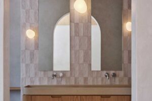 Koupelna s dvojitým umyvadlem, obloukovými zrcadly a jemnými obklady působí klidně a harmonicky