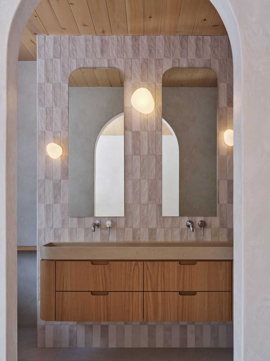 Koupelna s dvojitým umyvadlem, obloukovými zrcadly a jemnými obklady působí klidně a harmonicky