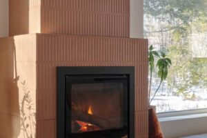 Detail krbu s keramickým obkladem a výhledem do lesa zdůrazňuje propojení tepla a přírody