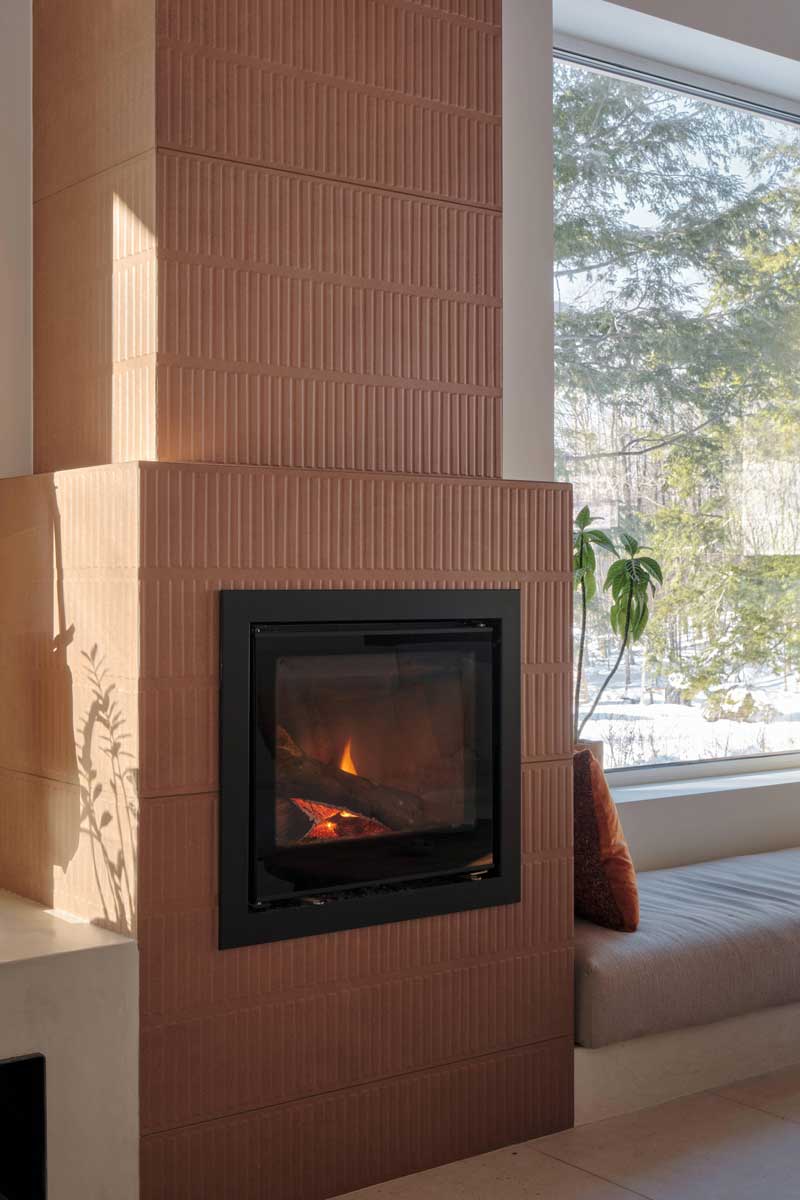 Detail krbu s keramickým obkladem a výhledem do lesa zdůrazňuje propojení tepla a přírody