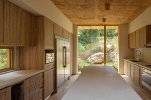 Kuchyň s velkým oknem orientovaným do přírody a přírodními materiály v interiéru.