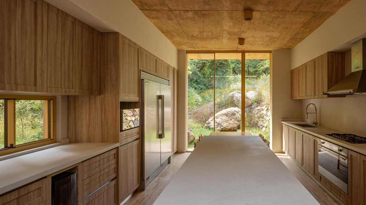 Kuchyň s velkým oknem orientovaným do přírody a přírodními materiály v interiéru.