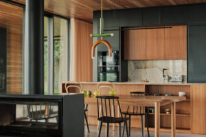 Moderní kuchyň v domě Casa Loredo kombinuje dřevo, černé plochy a kámen v klidném současném stylu.