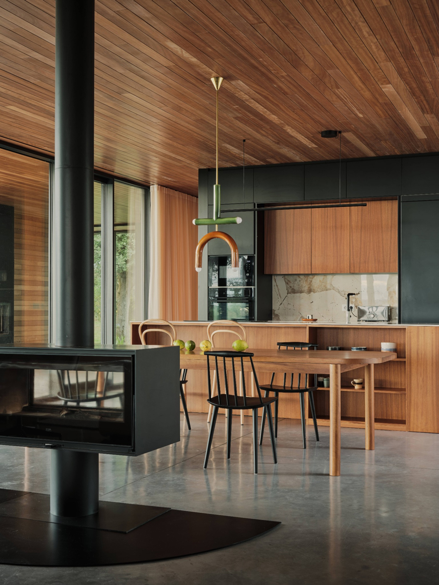 Moderní kuchyň v domě Casa Loredo kombinuje dřevo, černé plochy a kámen v klidném současném stylu.