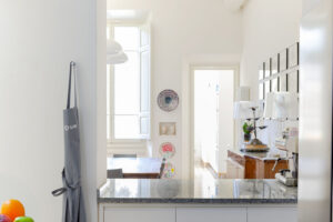 Malá florentská kuchyně propojená s jídelnou využívá světlý nábytek, žulovou pracovní desku a vysoké stropy plné denního světla.