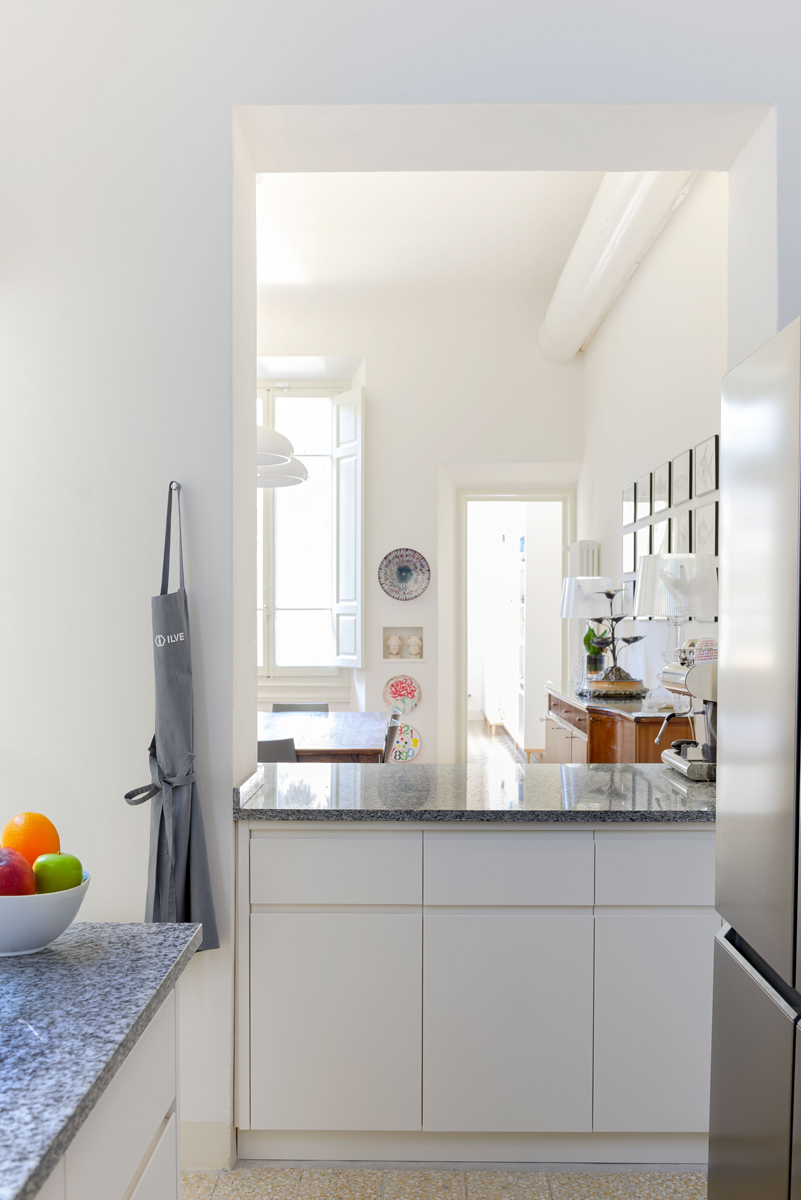 Malá florentská kuchyně propojená s jídelnou využívá světlý nábytek, žulovou pracovní desku a vysoké stropy plné denního světla.