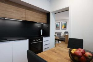 Kuchyň propojená s jídelním koutem nabízí praktické uspořádání a vizuální kontinuitu díky jednotné podlaze a materiálům.