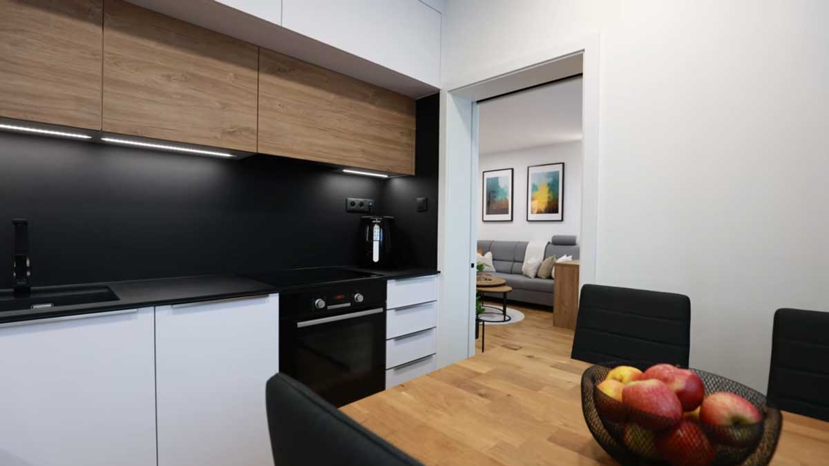 Kuchyň propojená s jídelním koutem nabízí praktické uspořádání a vizuální kontinuitu díky jednotné podlaze a materiálům.